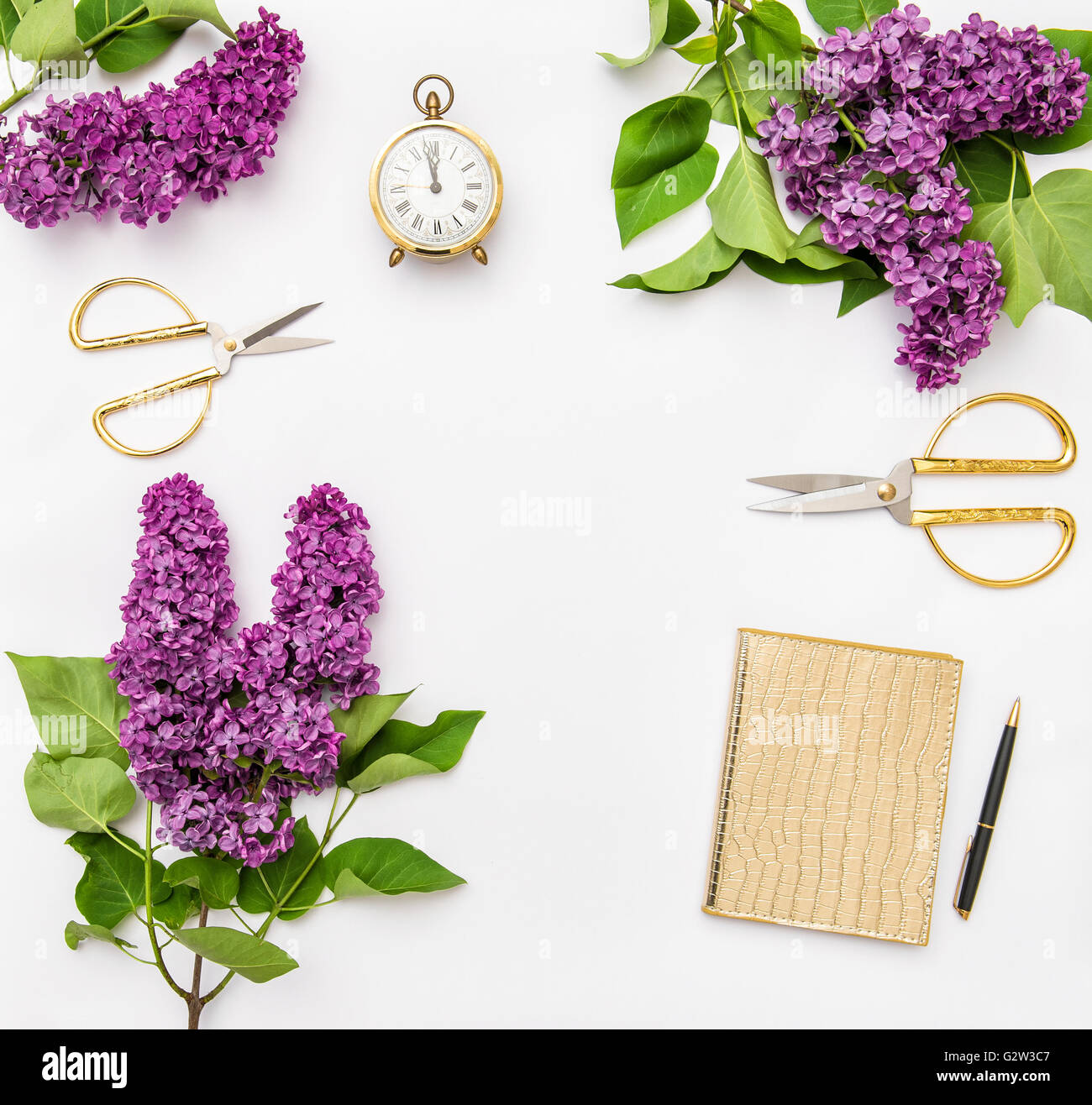 Lilac flowers, diary notebook, golden office supplies. Flat lay Stock