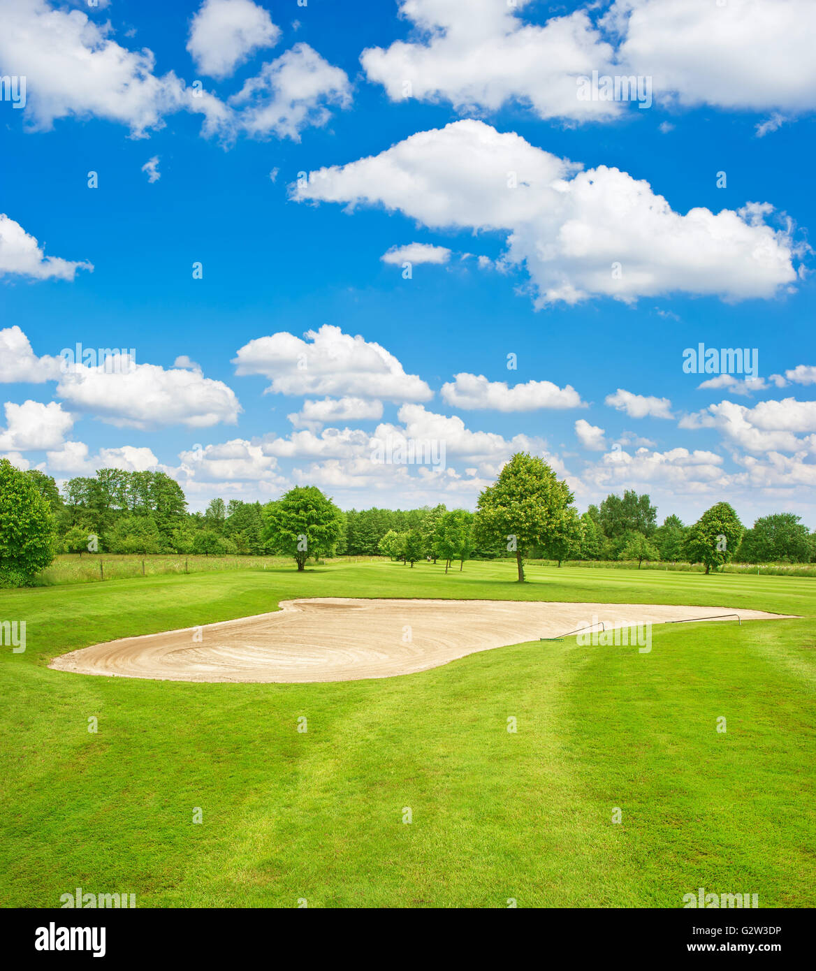 Green golf course field and blue cloudy sky. European nature landscape Stock Photo