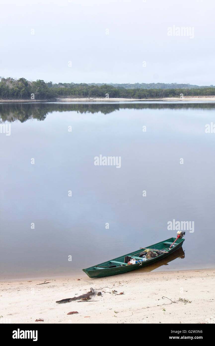 Old wooden boat moored to Amazon river shore in Brazil on a quiet scene Stock Photo