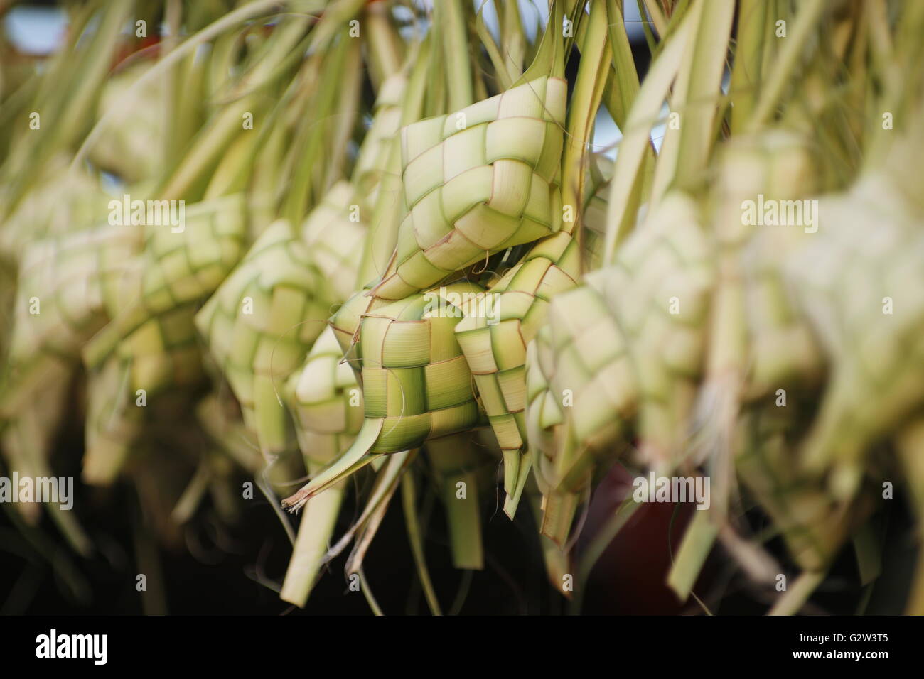 Ketupat, a type of dumpling made from rice packed inside a diamond-shaped container of woven palm leaf pouch. Stock Photo