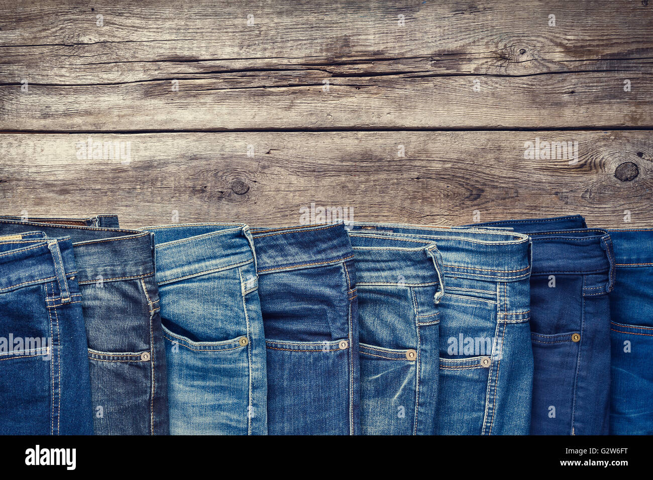 Fashion different jeans on wooden background. Retro toned Stock Photo -  Alamy