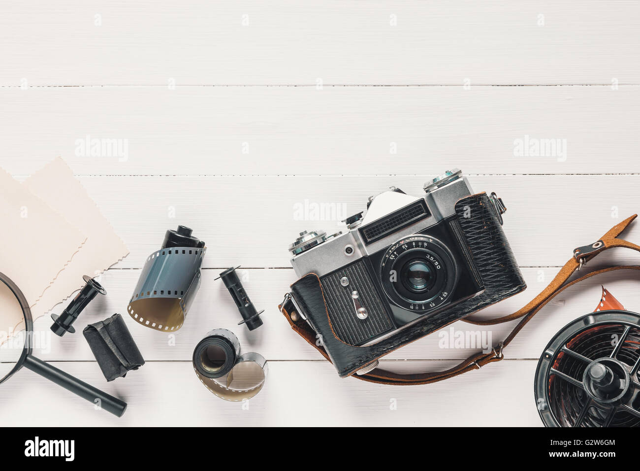 Retro camera, old photo film rolls, empty photos and magnifier on