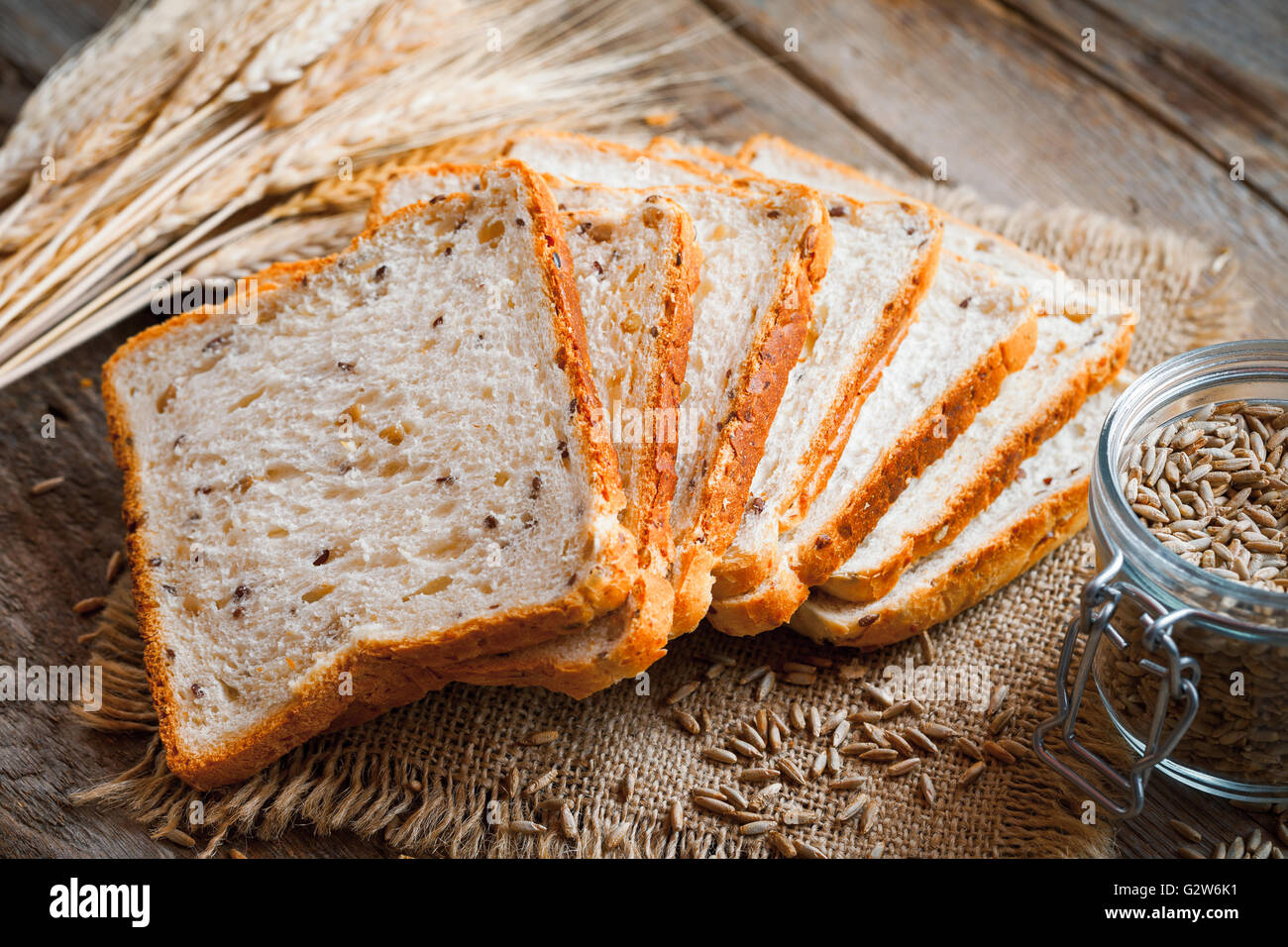 Wheat toast bread, spikes and wheat grains on kitchen table. Stock Photo