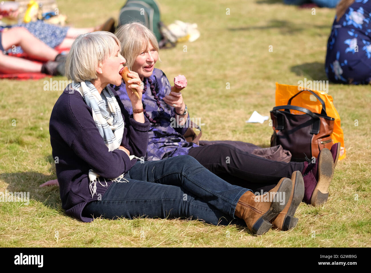 Hay Festival, Wales, UK - June 2016 -  Another very hot and sunny day at the Hay Festival with temperatures up to 20c. Two friends sit and enjoy their delicious Shepherds sheep milk ice cream on the Festival grass lawns. Stock Photo