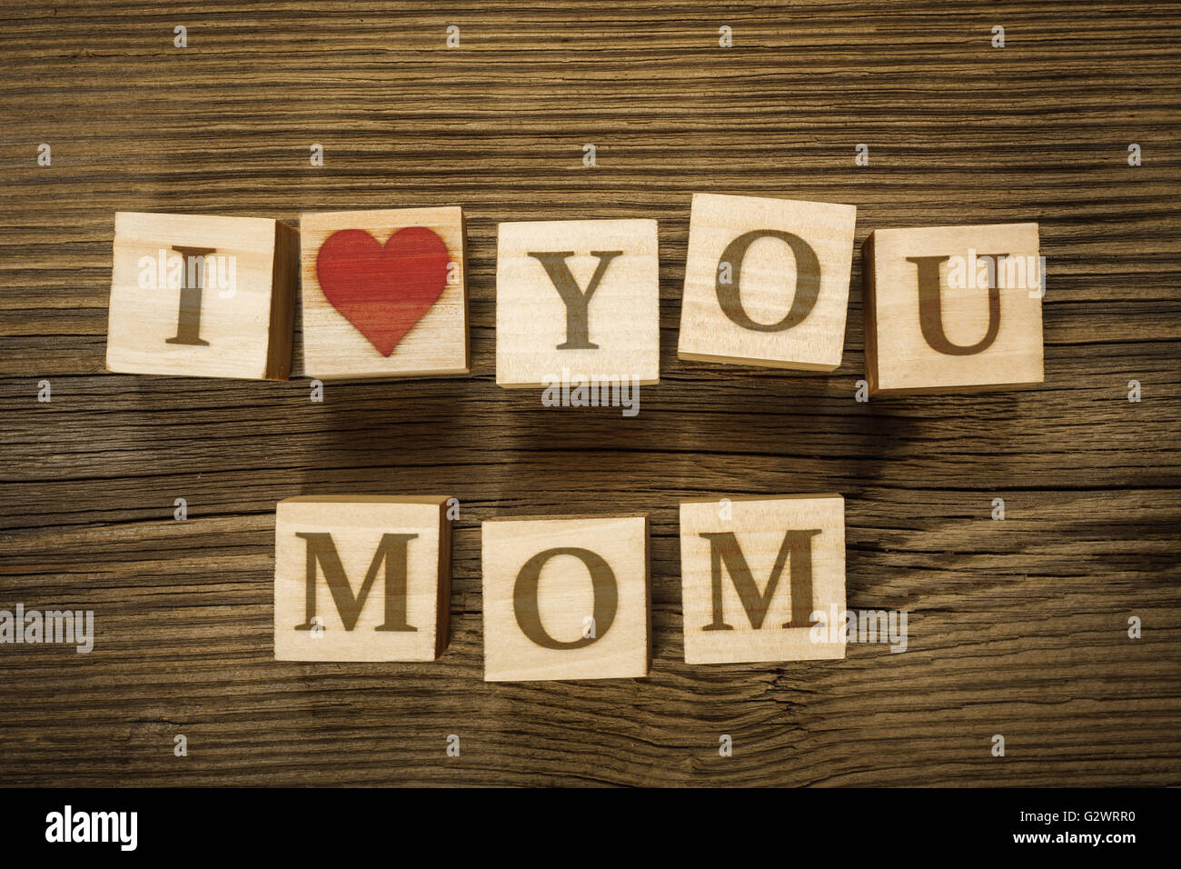 Message I LOVE YOU MOM made of letters on wooden blocks. Mothers Day. Letters and heart shape drawn by the author in a graphics Stock Photo