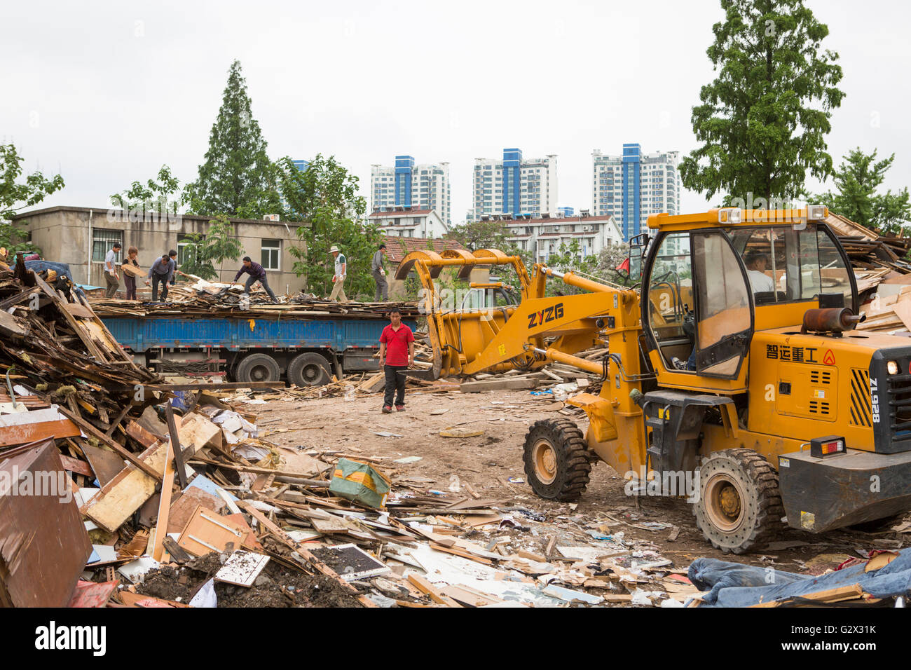 Demolition of old buildings with workers and a bulldozer to make place for new apartments on the outside of the city Nanjing Stock Photo
