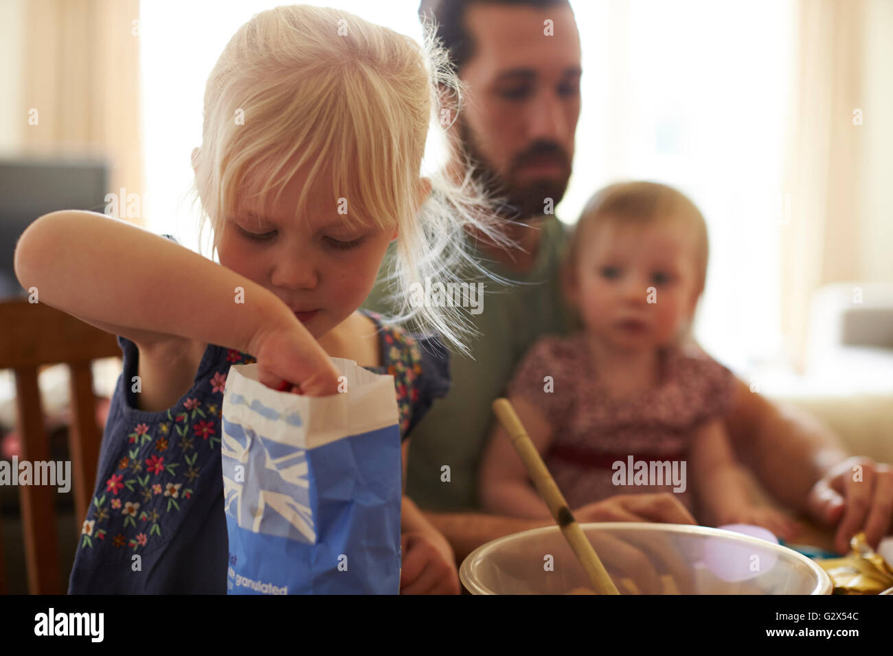 Father With Daughters At Home Baking Cakes Together Stock Photo