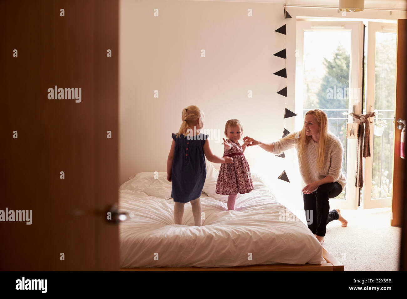 Mother Playing Game With Daughters In Bedroom Stock Photo