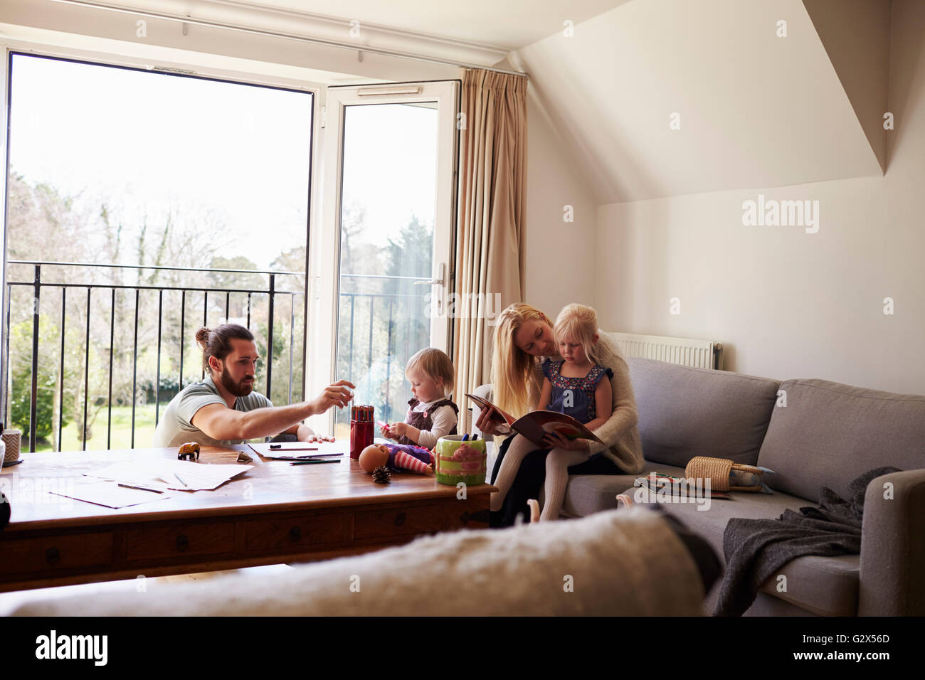 Family Drawing Pictures And Reading At Home Together Stock Photo