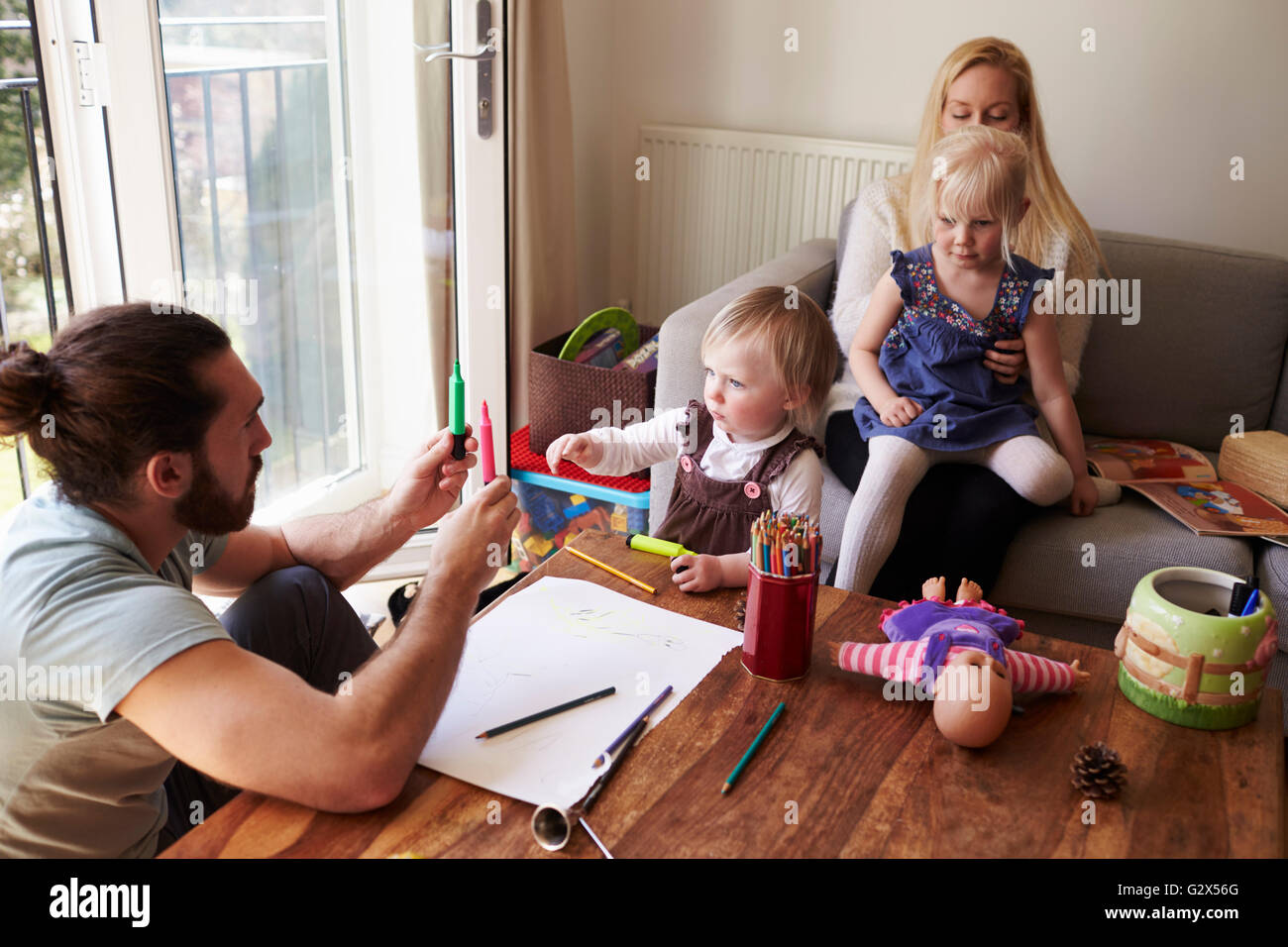 Family Sitting At Table And Drawing Pictures Together Stock Photo