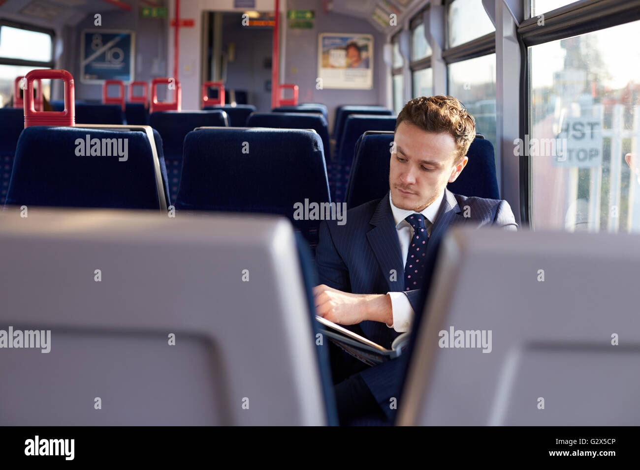 Businessman Commuting To Work Reading Newspaper On Train Stock Photo
