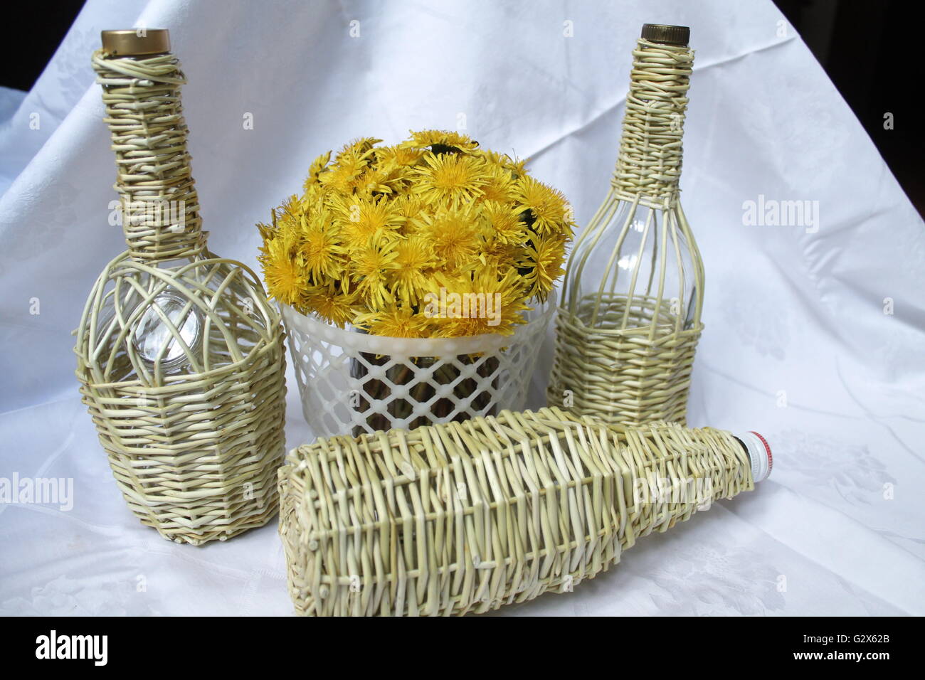 bouquet of yellow dandelion in basket and weave from willow glass bottles  crafts things for decor home Stock Photo