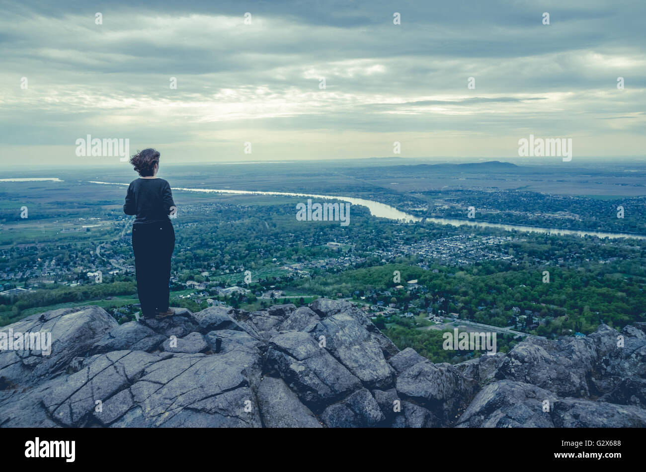 Woman standing alone on top of hill and looking at the landscape Stock Photo