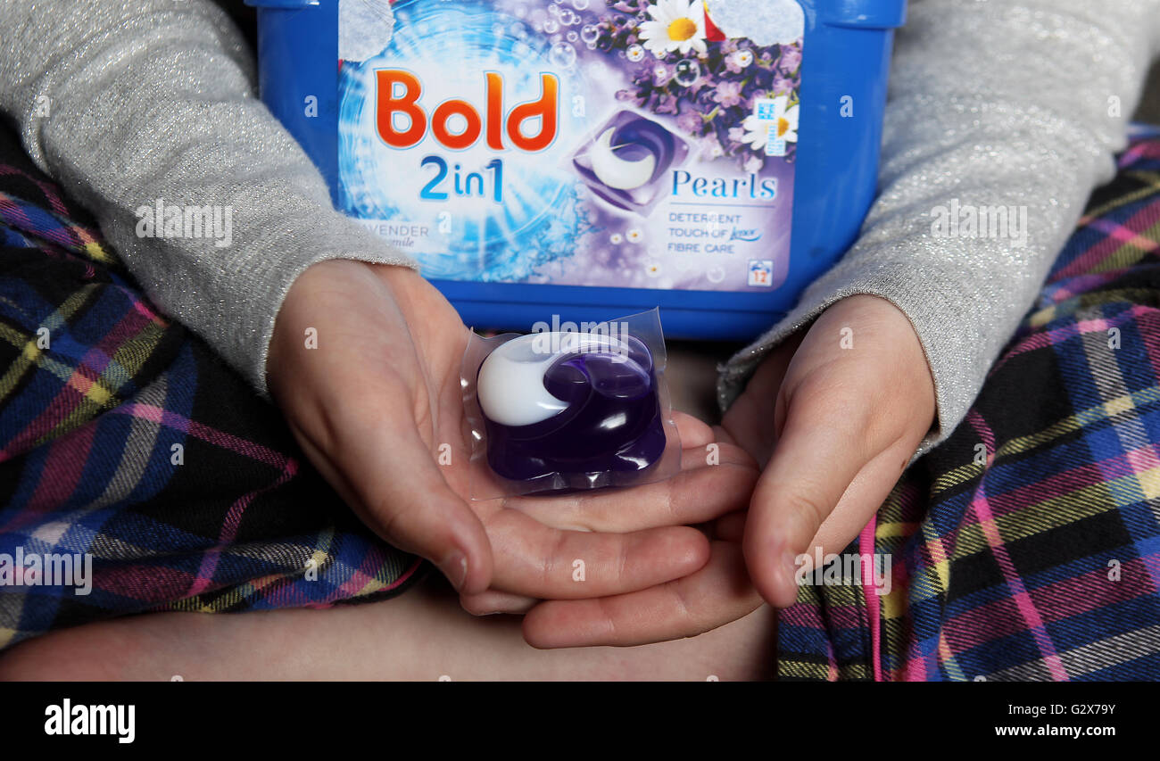 A child holds a laundry capsule, as children are mistaking dangerous laundry capsules for sweets at a rate of at least one incident every day, parents have been warned. Stock Photo