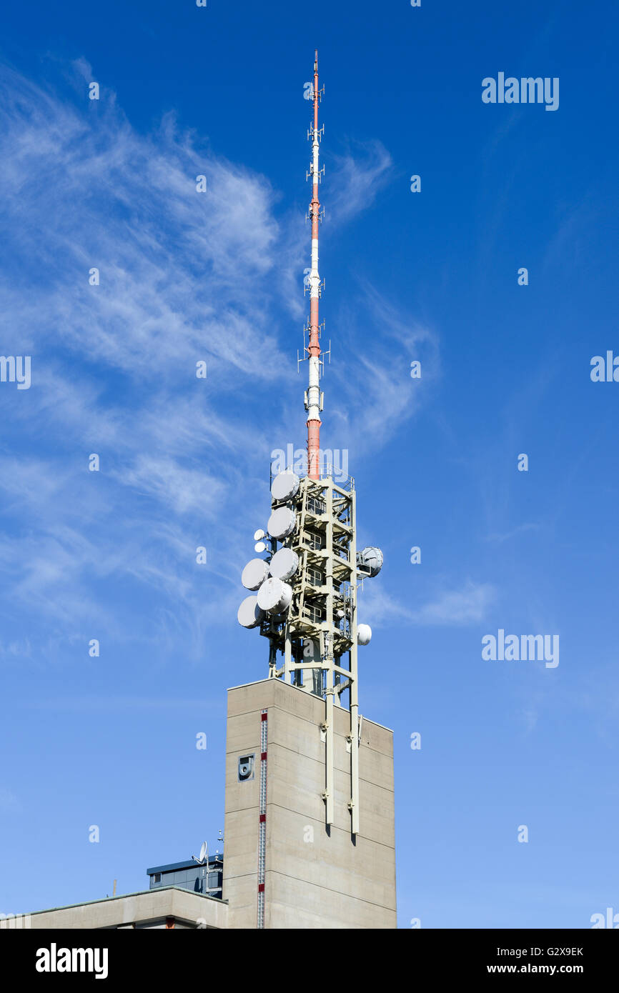 Telecommunication antenna with microwave link antennas over a blue sky Stock Photo