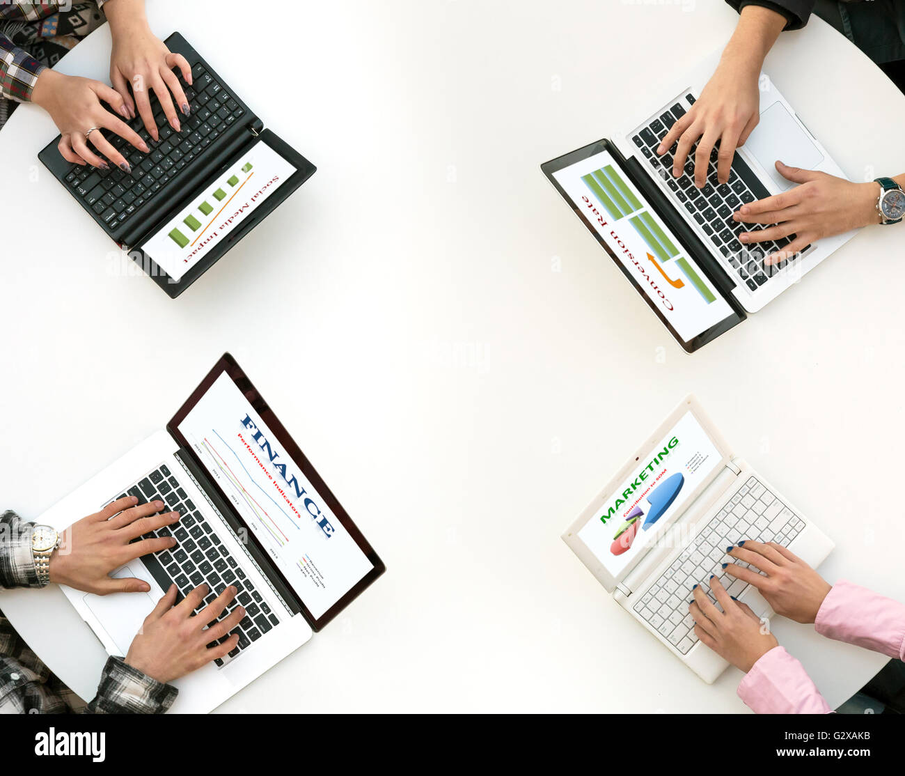 Top View of Rounded Desk with Four Laptops and People Hands Typing on Keyboard Stock Photo