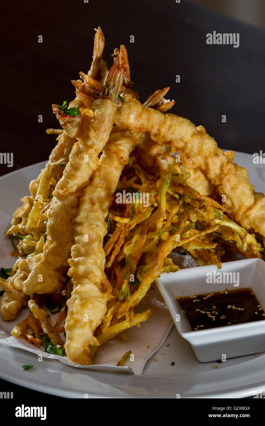 close up of a dish with tempura fried shrimp and vegetables with a soy