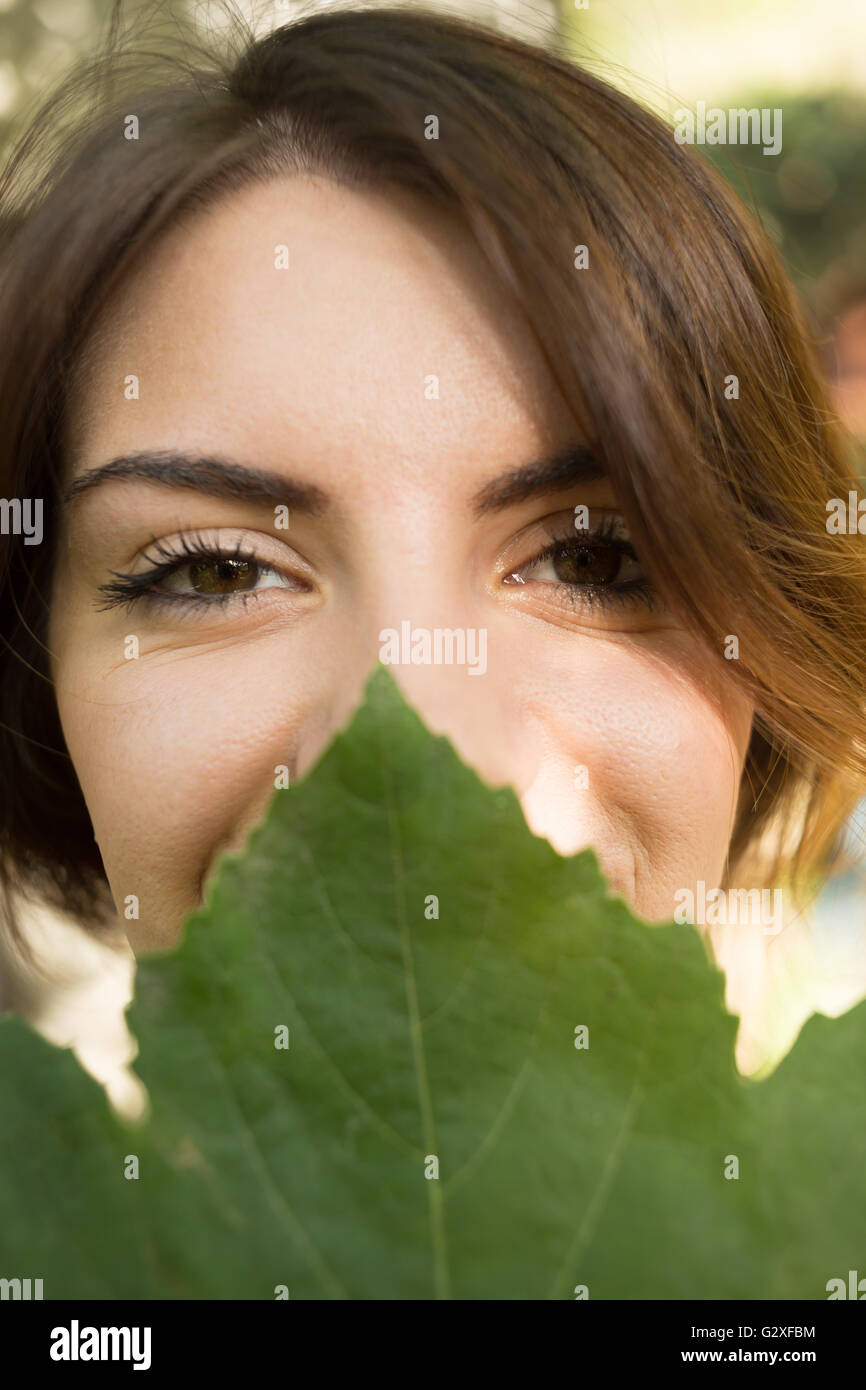 Face of beautiful woman is covered by green leaf, concept of beauty and ...