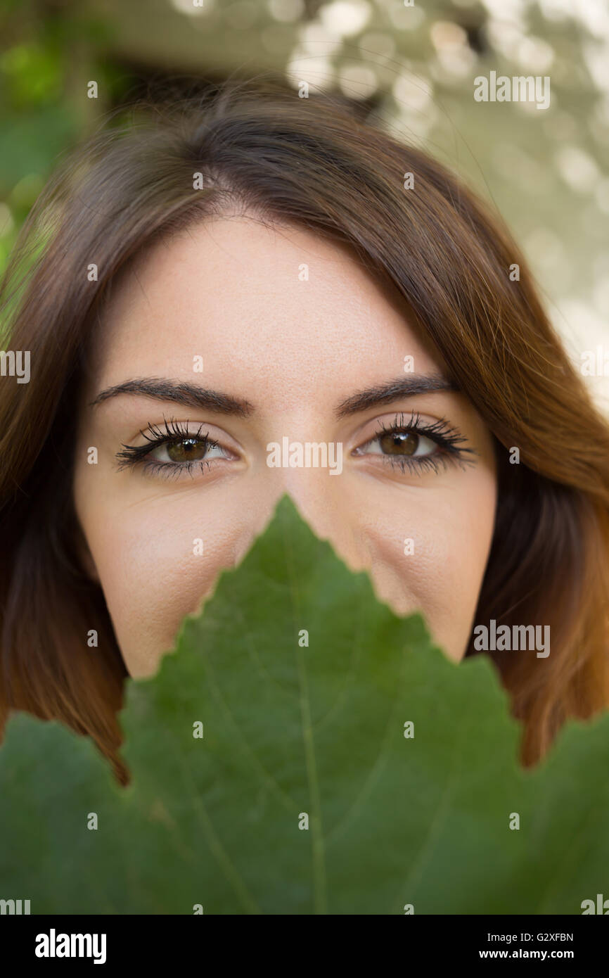 Face of beautiful woman is covered by green leaf, concept of beauty and ...