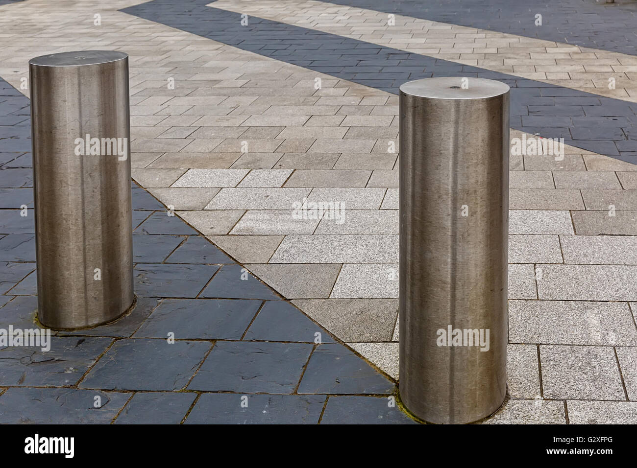 Stainless Steel bollard on grey pavement with a few lines of dark grey paving slabs Stock Photo