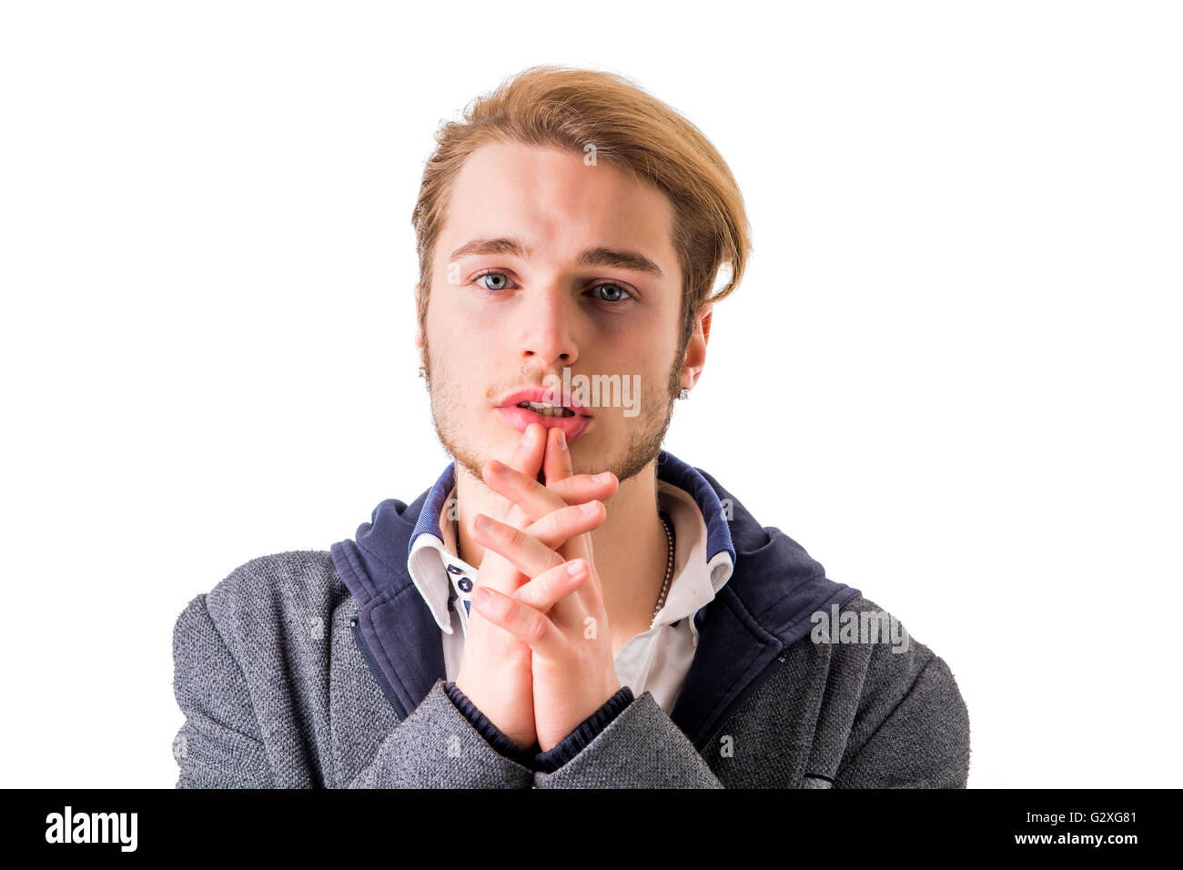 Needy, desperate young man pleading with hands joined as if praying to camera, isolated Stock Photo