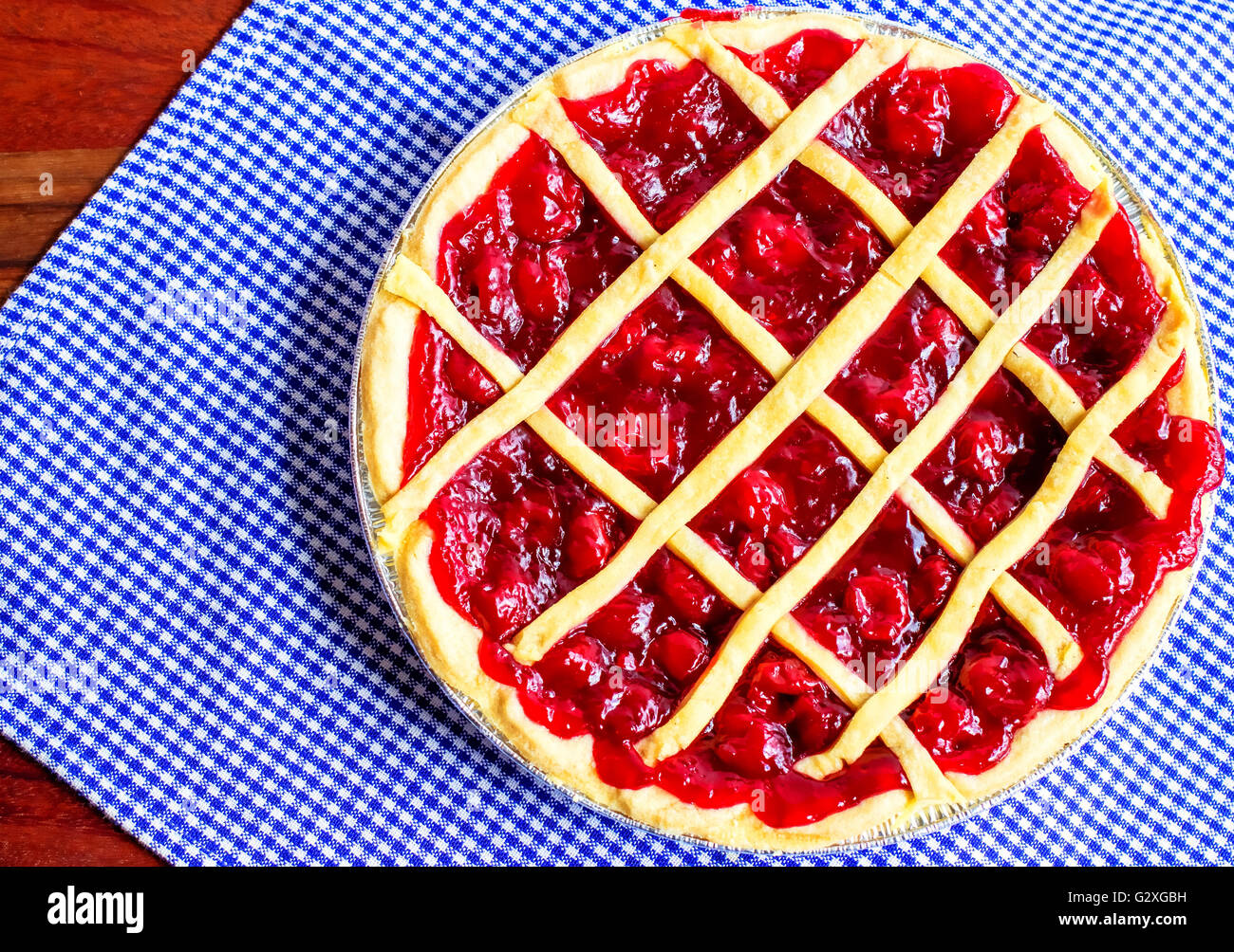 Sweet Cherry pie. Fresh from the oven hot home baked cherry pie on a blue and white gingham background. Stock Photo
