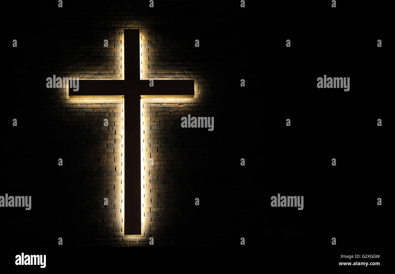 Illuminated Cross. Illuminated cross in horizontal orientation set against a brick wall with copy space. Stock Photo