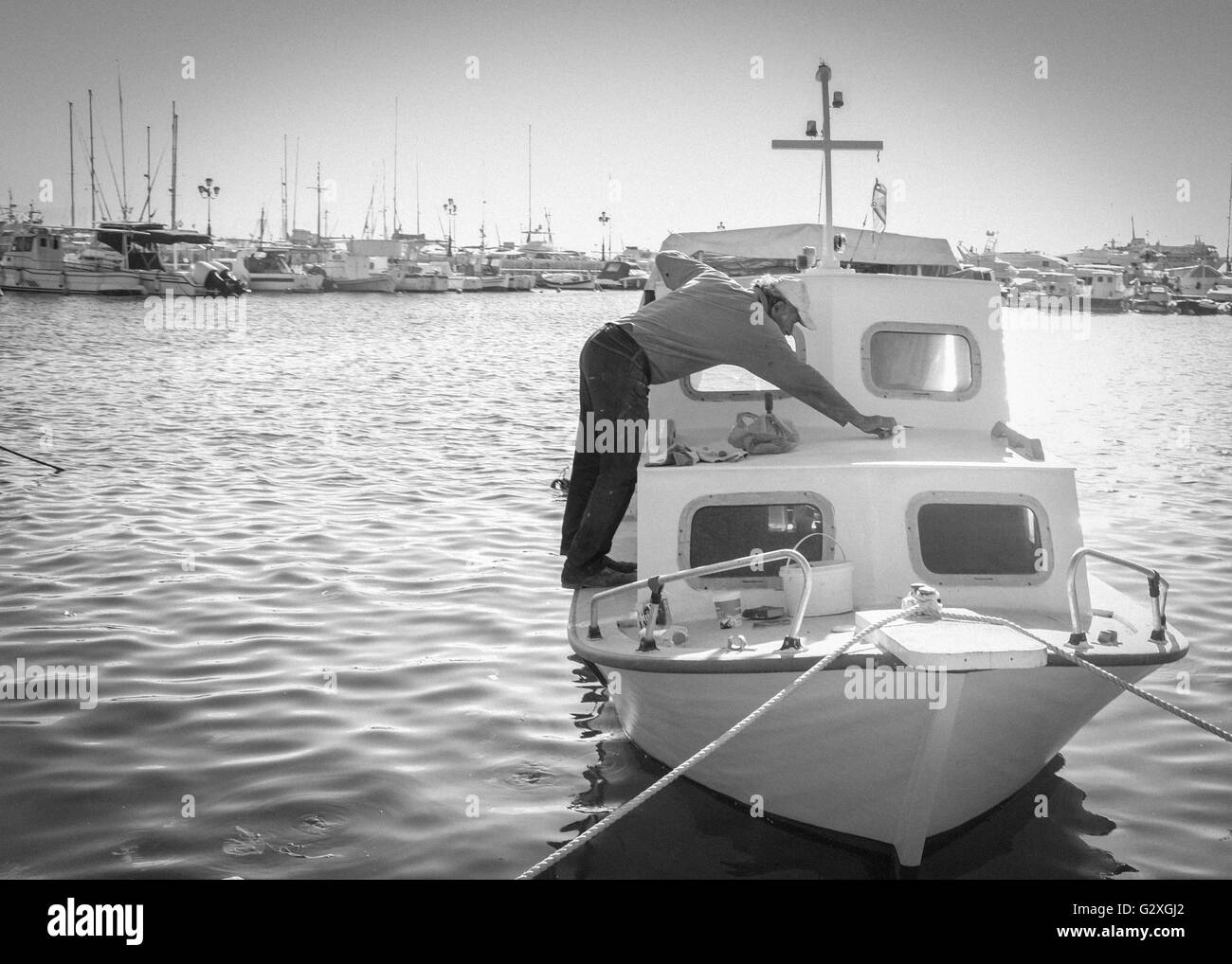 Sailir cleaning his boat in Aegina Port, Greece Stock Photo