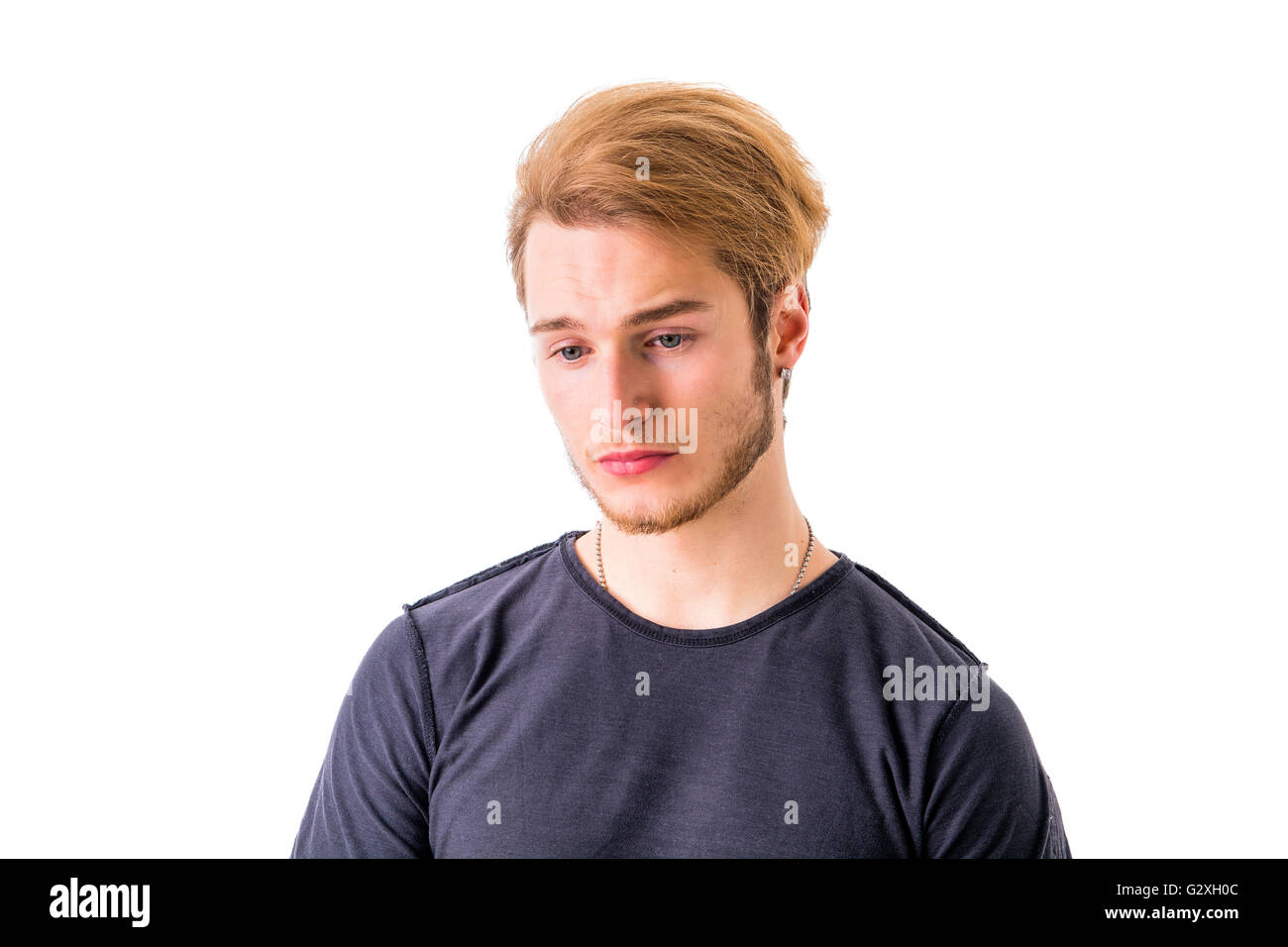 Sad or worried handsome young man looking down, isolated on white Stock Photo