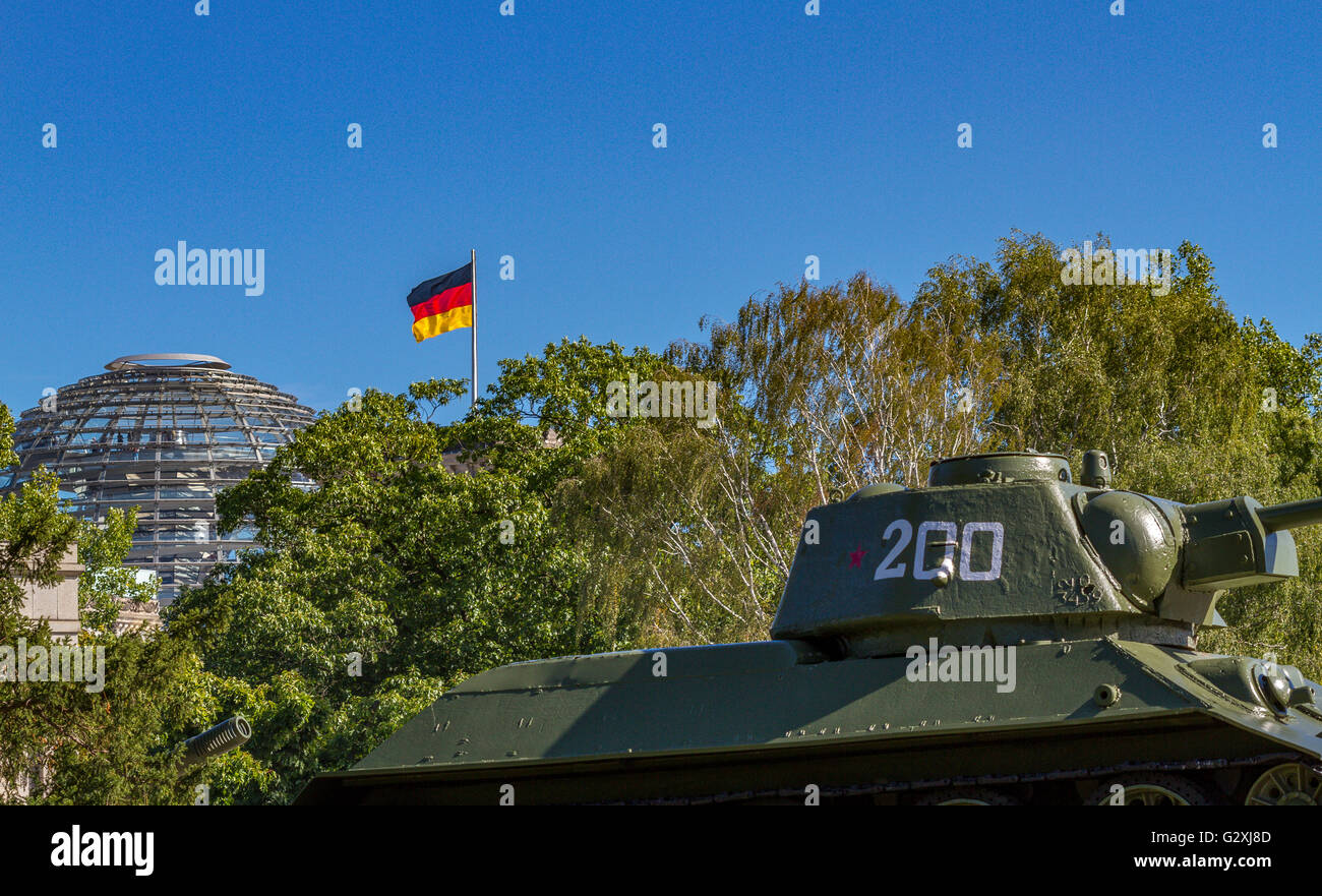 A T-34 Russian Tank at  the Soviet War Memorial in the Tiergarten, with the glass dome of The Reichstag Building visible through the trees, Berlin Stock Photo