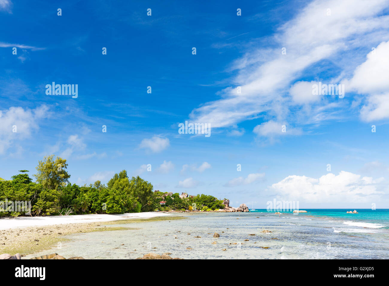 Low tide at Anse Severe in La Digue, Seychelles with palm trees and granite rocks Stock Photo