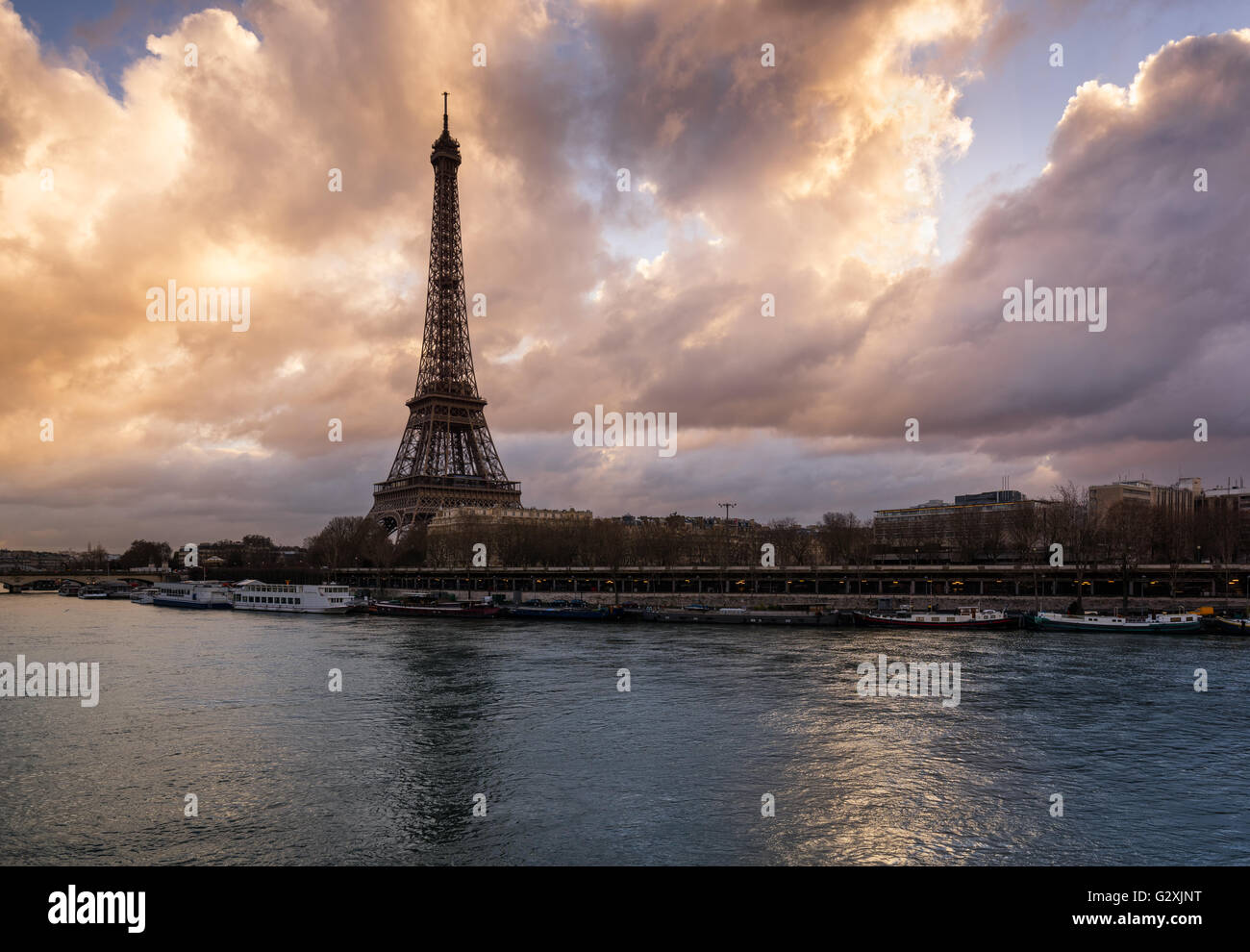 Luminous clouds the Eiffel Tower and the Seine River at sunrise. Port de Suffren, Paris, France Stock Photo
