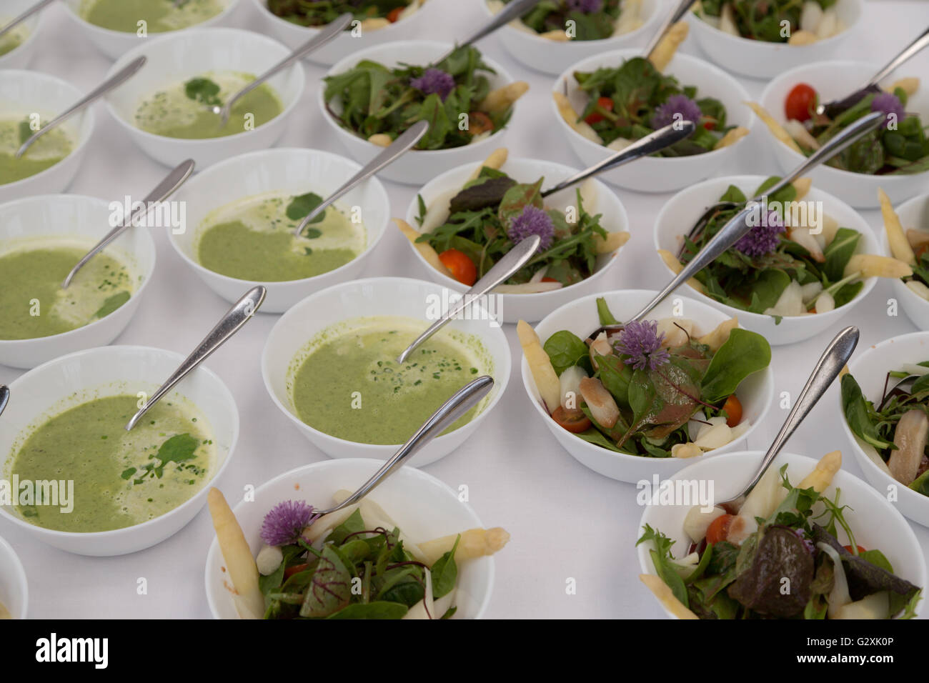 A photograph of some asparagus salad and soup in white bowls, being served as a starter. Stock Photo