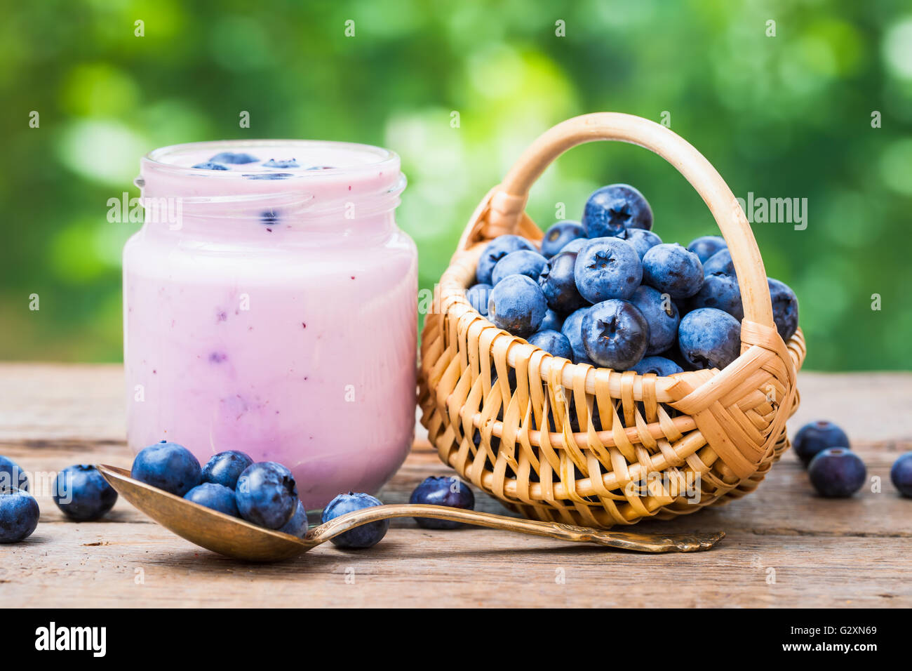 Fresh blueberries yogurt in jar and small basket of bilberries. Stock Photo