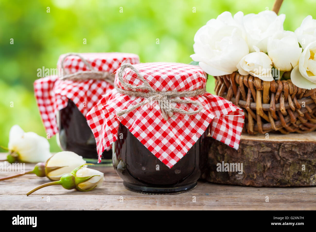 Jars of jam and basket of white roses Stock Photo Alamy