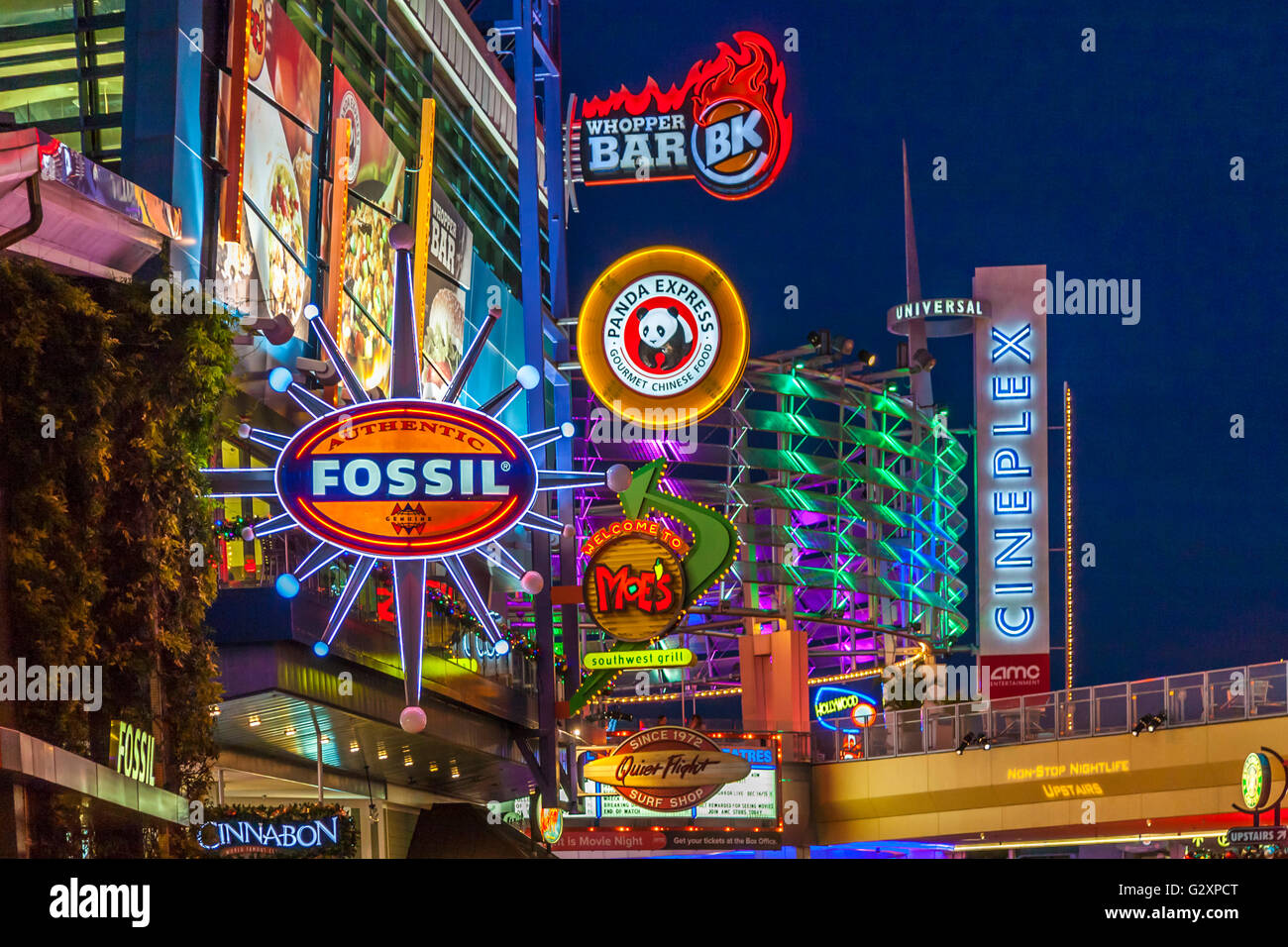 Brightly colored neon signs advertise restaurants and movie theaters at Universal Studio's City Walk in Orlando, Florida Stock Photo