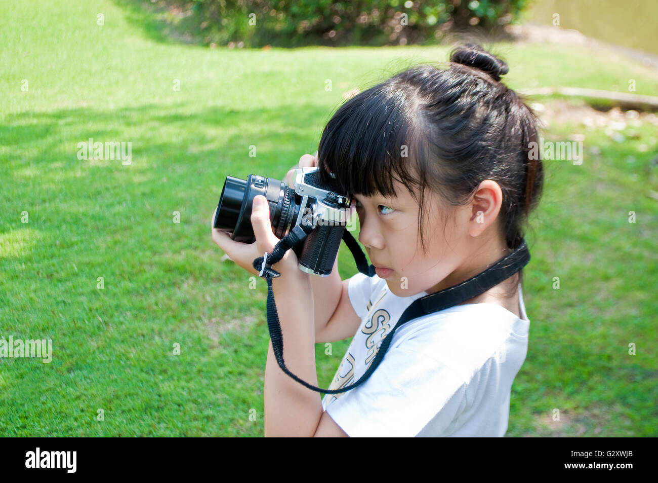 Seven years old girl taking photograph using single lens reflex camera