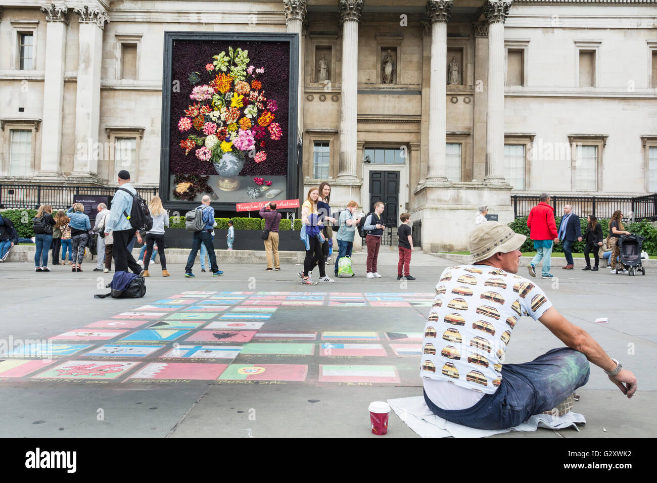 Pavement artist in Trafalgar Square, London, UK - colourful chalk drawings of national flags Stock Photo