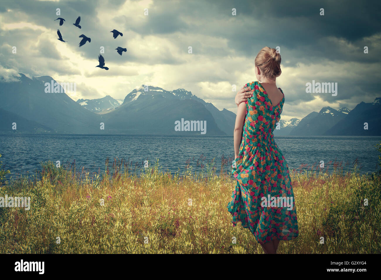Girl in Iceland is in a dress on the shore of the fjord, and looking at the birds Stock Photo