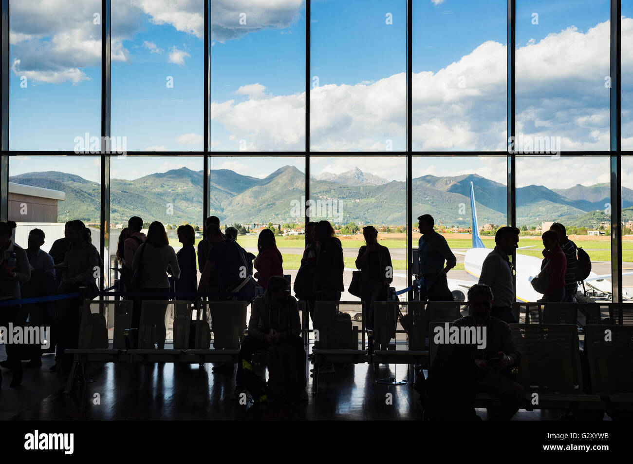 Silhouette queue people waiting in line for airplane in terminal with mountain background, Milano Bergamo airport Stock Photo