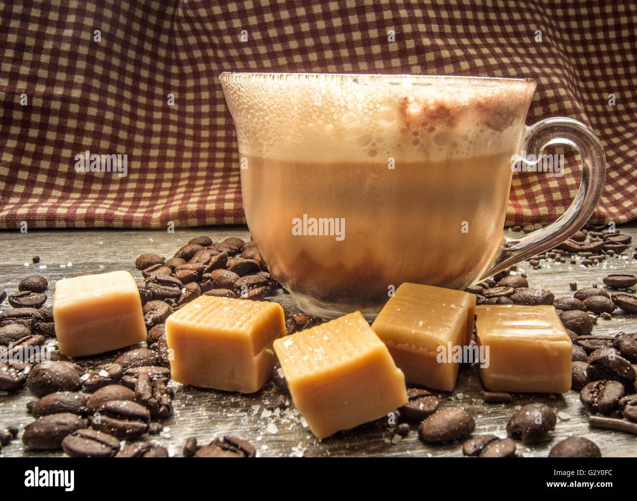 Salted Caramel Latte. Salted caramel latte surrounded by coffee beans, caramels, and sea salt. Shot from a side view with select Stock Photo