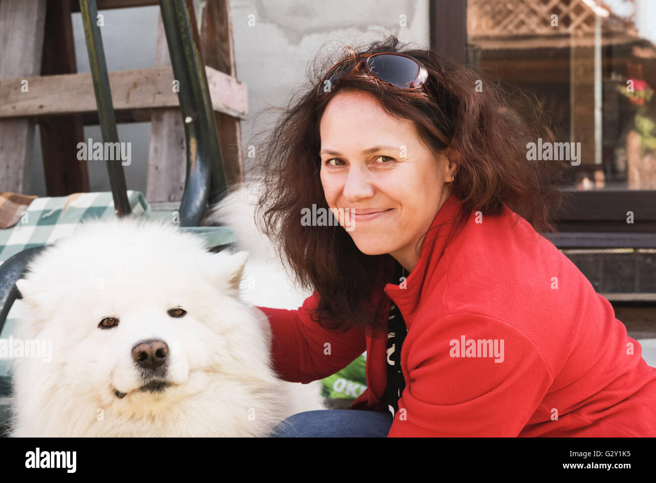 Happy young Caucasian woman with white fluffy Samoyed dog Stock Photo