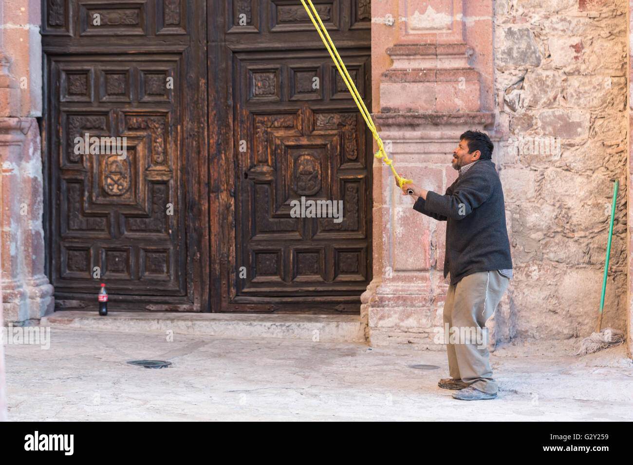 The bell ringer of the Parroquia de San Miguel Arcangel church pulls the rope to ring the bells in Jardin Square in San Miguel de Allende, Mexico. Stock Photo