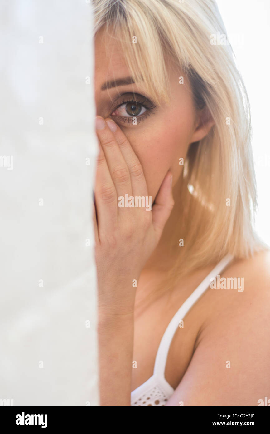 Young woman hiding behind a wall Stock Photo