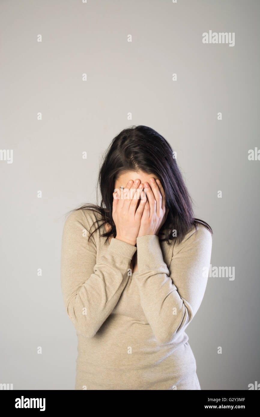 Woman hiding face with hands Stock Photo