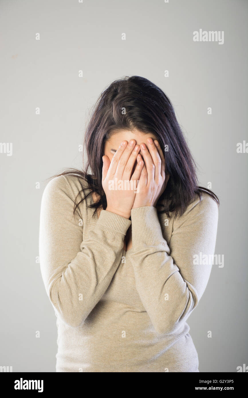 Woman hiding face with hands Stock Photo