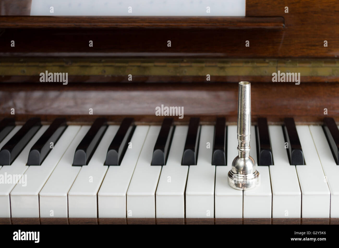 A trumpet mouthpiece upon the piano keys, close up Stock Photo