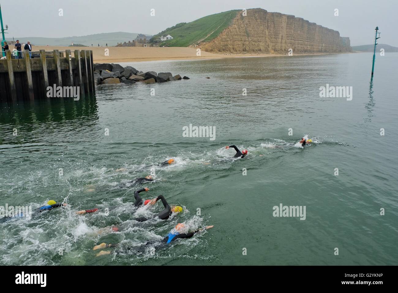 West Bay, Dorset, UK. 5 June 2016. Competitors swim out of West Bay Harbour on the first stage of the inaugural West Bay Triathlon. After swimming along Dorset's Jurassic coast competitors have a short run to collect their bikes then cycle through the landscape made famous in Thomas Hardy's novels before completing the final running section. Credit:  Tom Corban/Alamy Live News Stock Photo