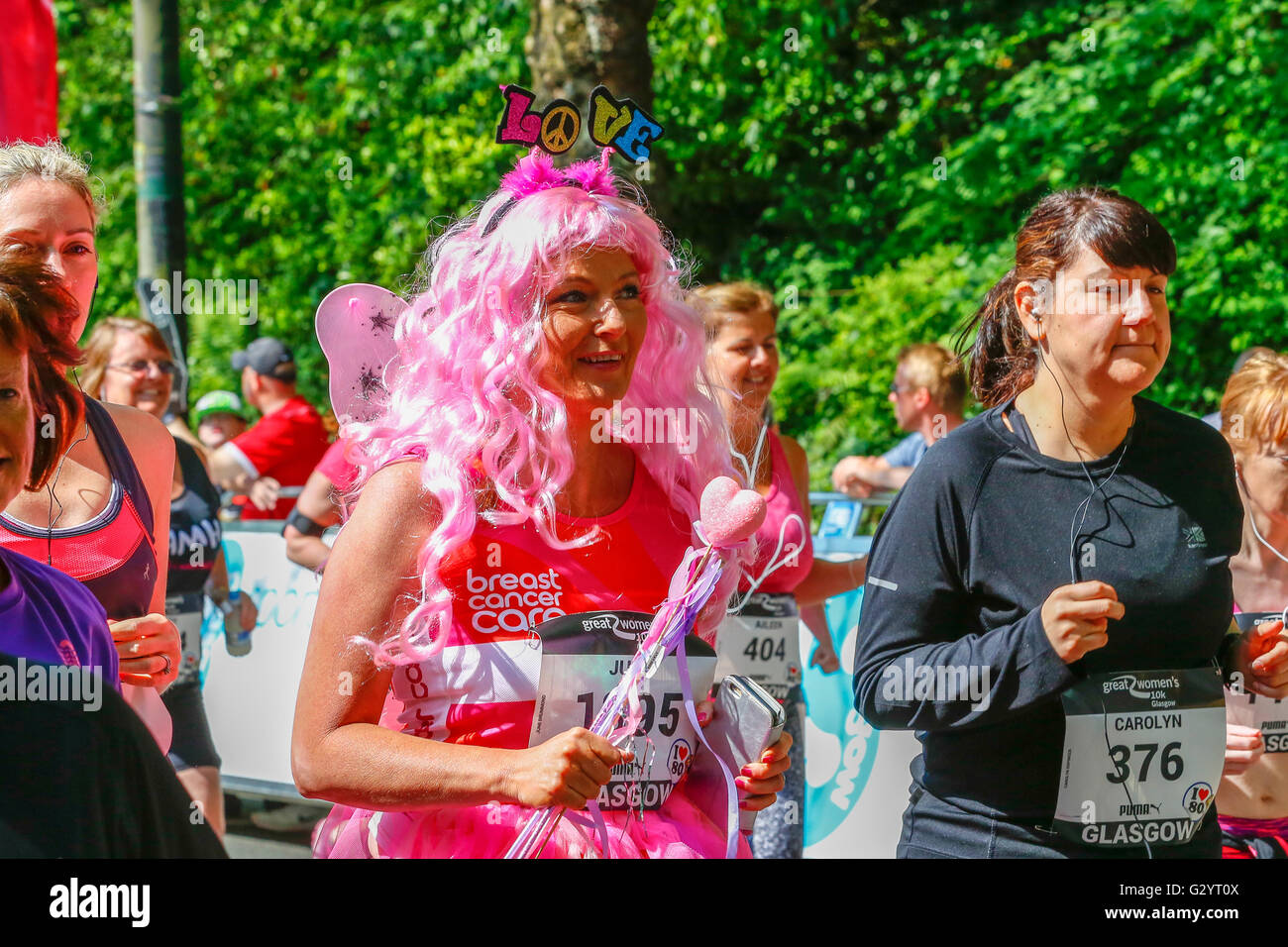 On a hot sunny June Sunday, with temperatures into the mid 20's, over 6000 women took part in the Glasgow "Great Run" starting in Kelvingrove Park and running through the city and along the River Clyde, encouraged along the way by musicians and cheerleaders. Because of the hot weather, a cold shower station was set up for the participants to run through and cool down. Stock Photo