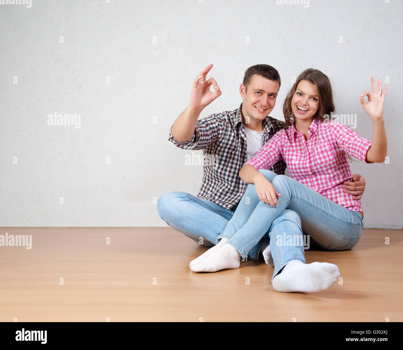 Portrait Of Happy Young Couple Sitting On Floor Looking Up Ready for ...